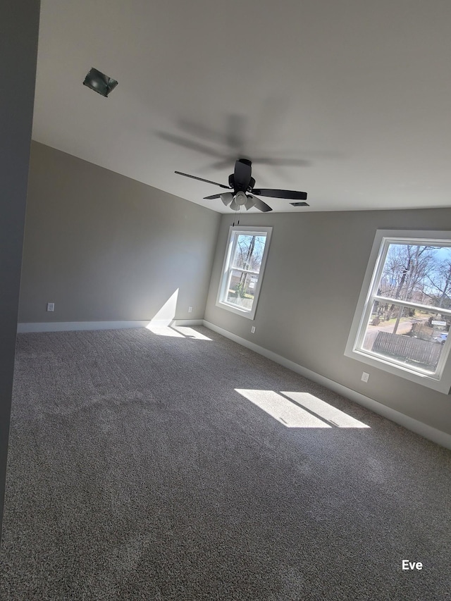 empty room featuring visible vents, carpet flooring, a ceiling fan, and baseboards