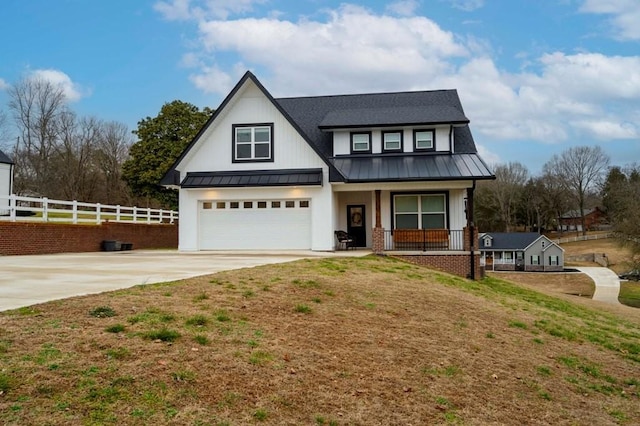 modern farmhouse style home featuring fence, a standing seam roof, covered porch, concrete driveway, and metal roof