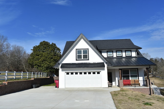 modern farmhouse featuring driveway, a standing seam roof, fence, covered porch, and metal roof