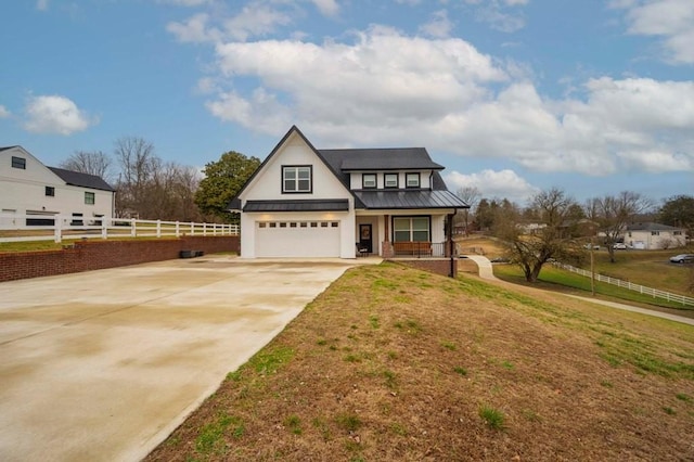 view of front of house with a front lawn, a standing seam roof, fence, concrete driveway, and metal roof