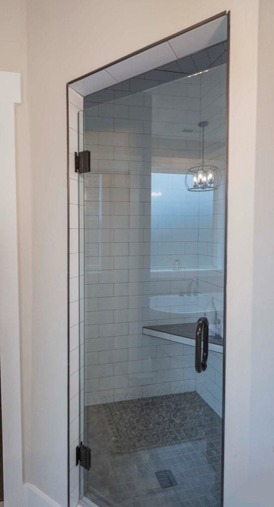 bathroom with a notable chandelier and a stall shower