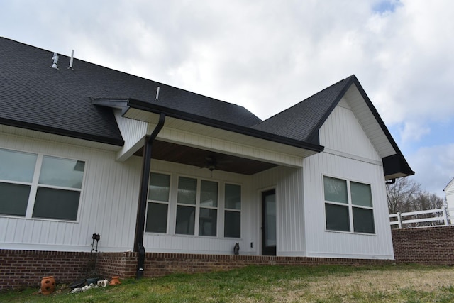 rear view of property featuring a shingled roof, fence, and ceiling fan