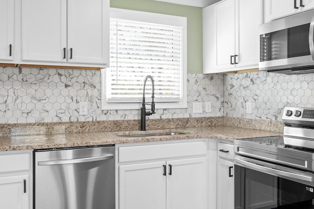 kitchen featuring white cabinets, stainless steel appliances, light stone counters, and sink