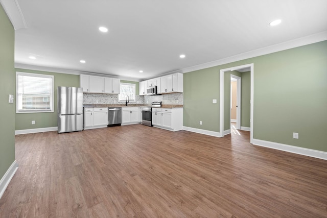 kitchen featuring ornamental molding, stainless steel appliances, white cabinetry, and hardwood / wood-style floors