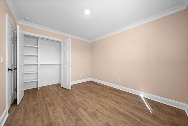 unfurnished bedroom with a closet, ornamental molding, and hardwood / wood-style flooring