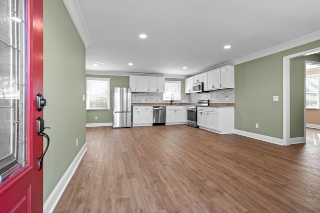 kitchen with stainless steel appliances, crown molding, and white cabinetry