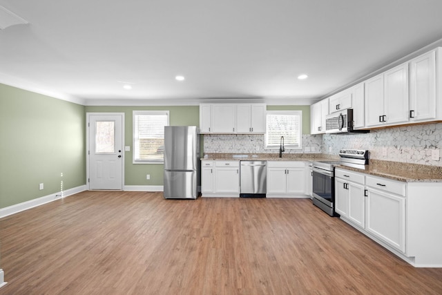 kitchen with appliances with stainless steel finishes, stone countertops, decorative backsplash, and white cabinetry