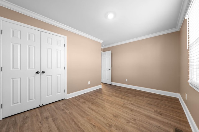 unfurnished bedroom featuring ornamental molding, a closet, and hardwood / wood-style flooring