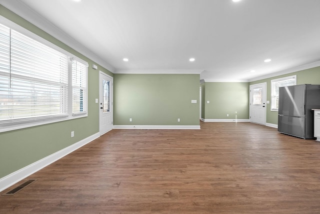 unfurnished living room featuring a healthy amount of sunlight and crown molding