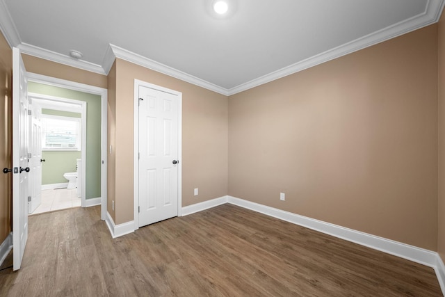 unfurnished bedroom with a closet, crown molding, and hardwood / wood-style flooring