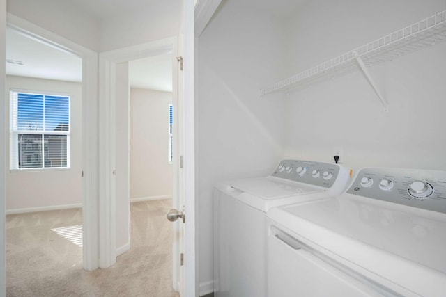 washroom with washing machine and clothes dryer and light colored carpet