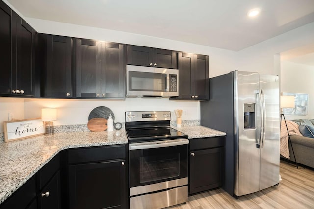 kitchen featuring light stone counters, light wood-type flooring, and stainless steel appliances