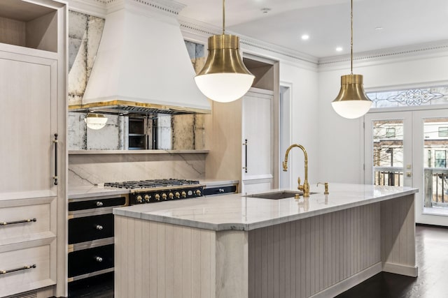 kitchen featuring custom exhaust hood, light stone countertops, a kitchen island with sink, and tasteful backsplash