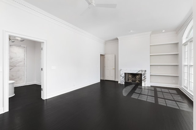 unfurnished living room featuring a wealth of natural light, a premium fireplace, built in features, and dark wood-type flooring