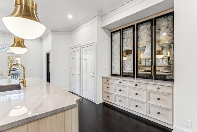 kitchen with light brown cabinets, dark wood-type flooring, sink, ornamental molding, and light stone counters