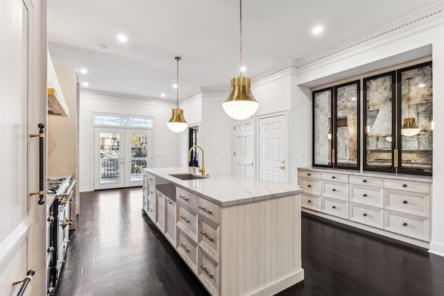 kitchen featuring light stone countertops, french doors, sink, a center island with sink, and hanging light fixtures