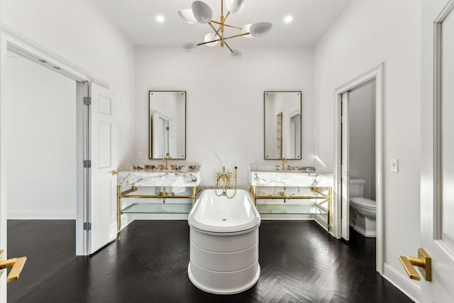 bathroom with parquet flooring, a bathtub, vanity, a chandelier, and toilet