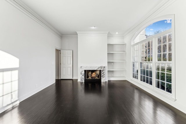 unfurnished living room with a fireplace, dark hardwood / wood-style flooring, built in features, and crown molding