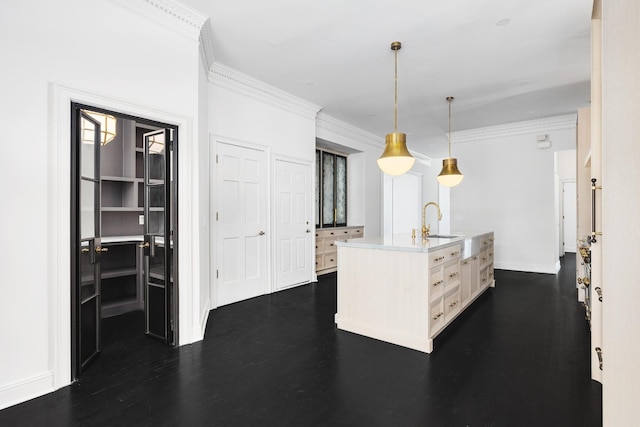 kitchen featuring pendant lighting, sink, crown molding, and an island with sink