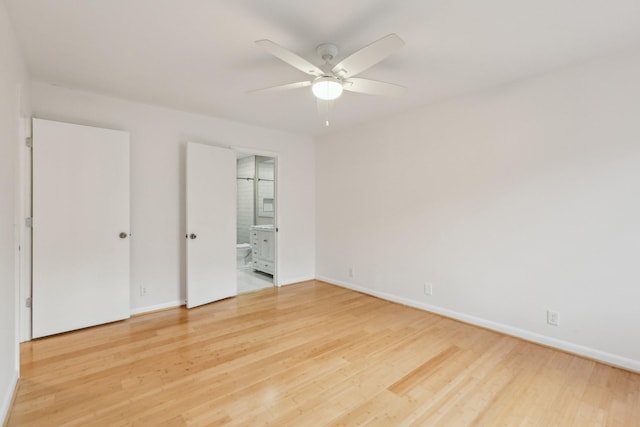 unfurnished bedroom featuring ceiling fan, ensuite bath, and hardwood / wood-style flooring