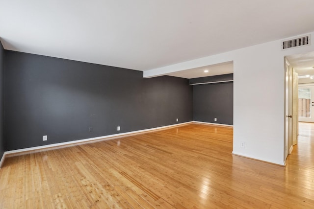 empty room with light hardwood / wood-style flooring and beam ceiling