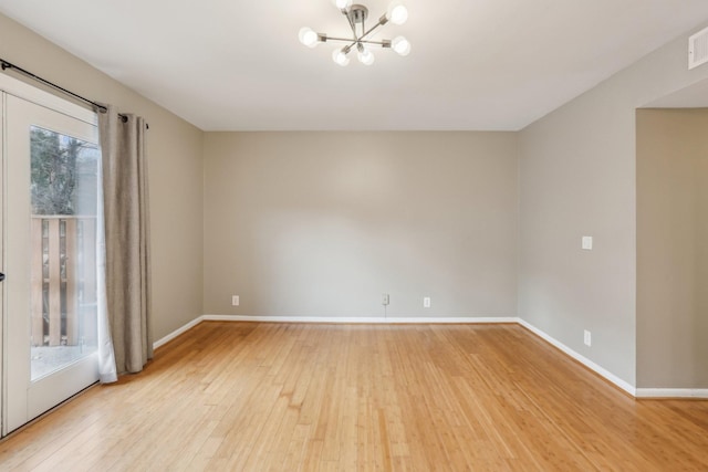 unfurnished room featuring light wood-type flooring and an inviting chandelier