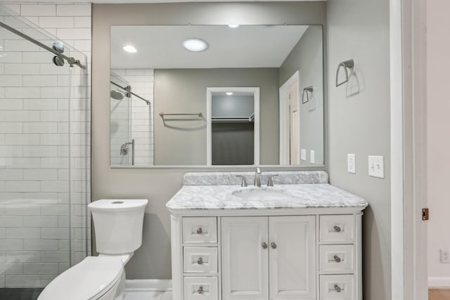 bathroom with a shower with shower door, toilet, and vanity