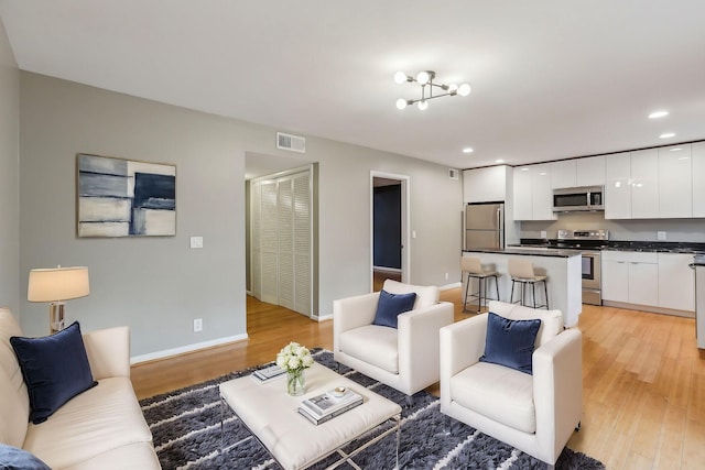 living room with an inviting chandelier and light hardwood / wood-style floors