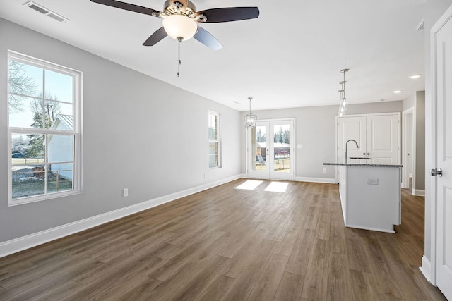 unfurnished living room with ceiling fan with notable chandelier and dark hardwood / wood-style floors