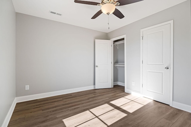 unfurnished bedroom featuring ceiling fan, dark hardwood / wood-style flooring, and a closet