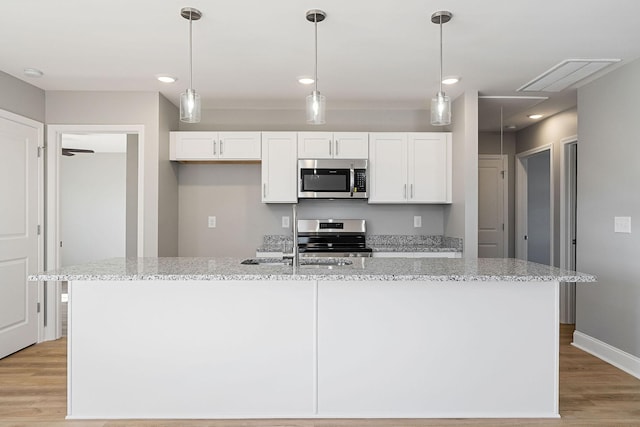 kitchen featuring white cabinetry, light stone counters, stainless steel appliances, and a kitchen island with sink