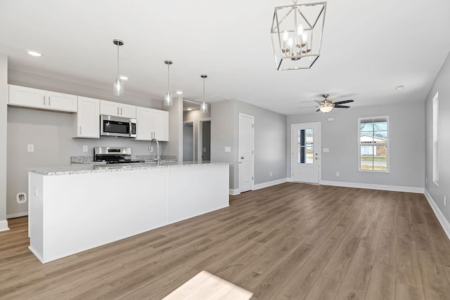 kitchen featuring light stone countertops, pendant lighting, white cabinets, and stainless steel appliances