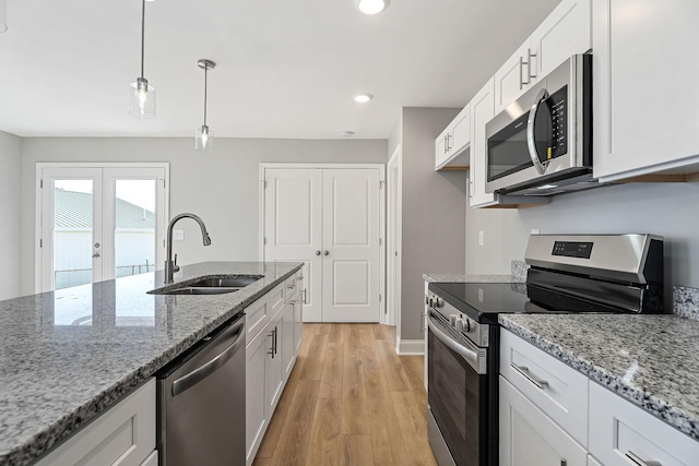 kitchen with french doors, white cabinets, sink, hanging light fixtures, and stainless steel appliances