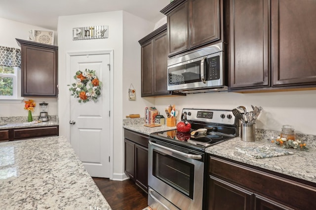 kitchen with dark brown cabinets, dark hardwood / wood-style floors, light stone countertops, and stainless steel appliances