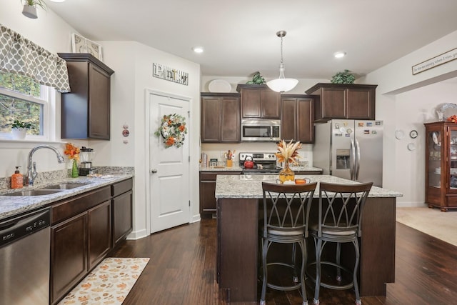 kitchen with decorative light fixtures, a center island, sink, and appliances with stainless steel finishes