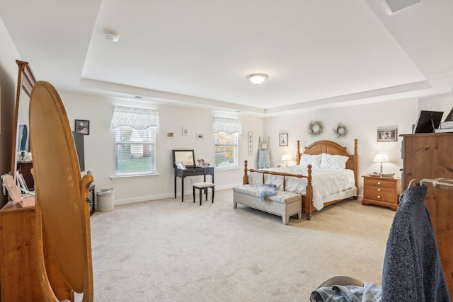 bedroom featuring a raised ceiling and light colored carpet