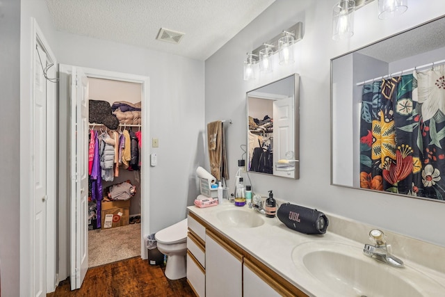 bathroom featuring vanity, a textured ceiling, hardwood / wood-style flooring, and toilet