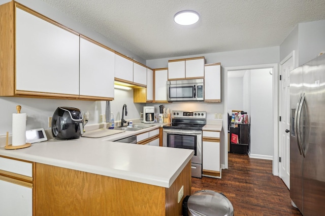 kitchen featuring kitchen peninsula, a textured ceiling, stainless steel appliances, sink, and white cabinets