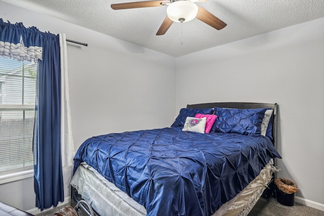 carpeted bedroom featuring ceiling fan and a textured ceiling