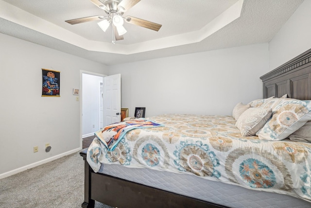 carpeted bedroom with a raised ceiling, ceiling fan, and a textured ceiling