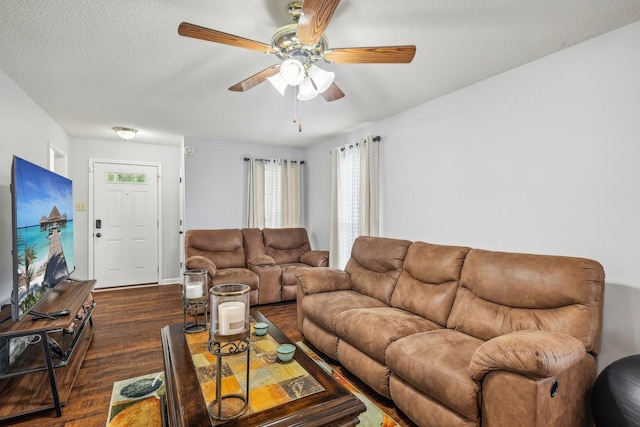 living room featuring ceiling fan, dark wood-type flooring, and a textured ceiling