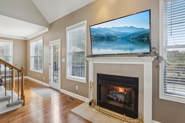 living room with a tiled fireplace, a healthy amount of sunlight, vaulted ceiling, and hardwood / wood-style flooring