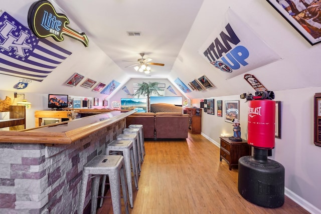 bar with lofted ceiling, ceiling fan, and hardwood / wood-style flooring