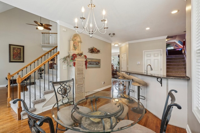 dining space featuring ceiling fan with notable chandelier, light wood-type flooring, ornamental molding, and sink