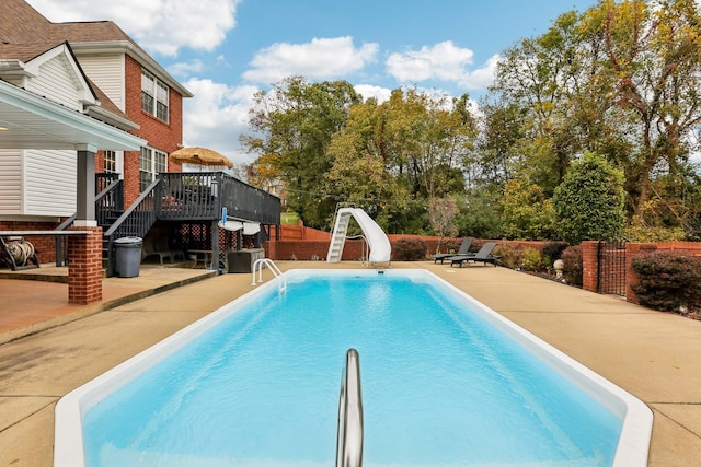 view of swimming pool featuring a water slide, a patio area, and a wooden deck