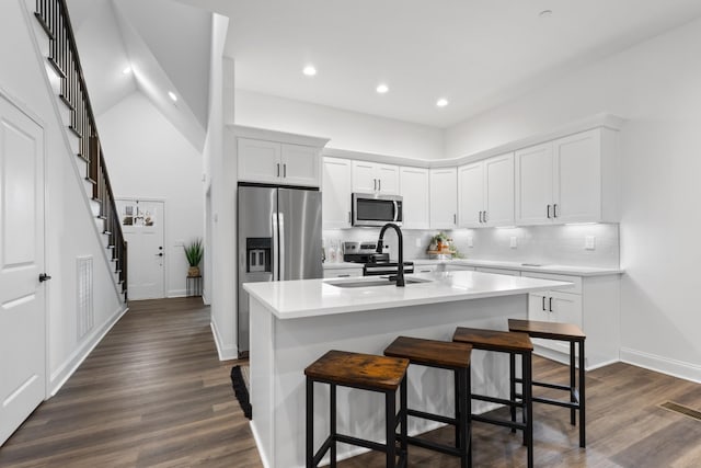 kitchen featuring white cabinets, stainless steel appliances, a center island with sink, and sink