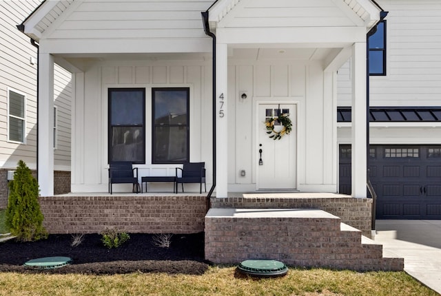 view of exterior entry featuring board and batten siding, a porch, concrete driveway, and an attached garage