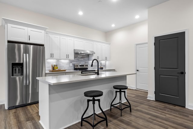 kitchen with stainless steel fridge, sink, an island with sink, white cabinetry, and range hood