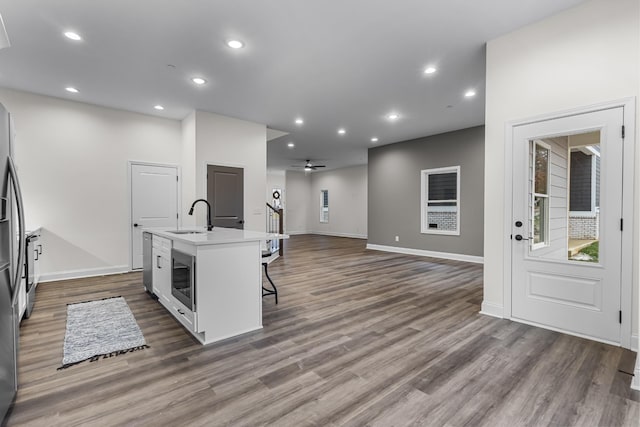 kitchen featuring a kitchen breakfast bar, sink, ceiling fan, an island with sink, and dark hardwood / wood-style flooring