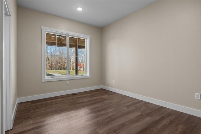 unfurnished room featuring baseboards and dark wood finished floors